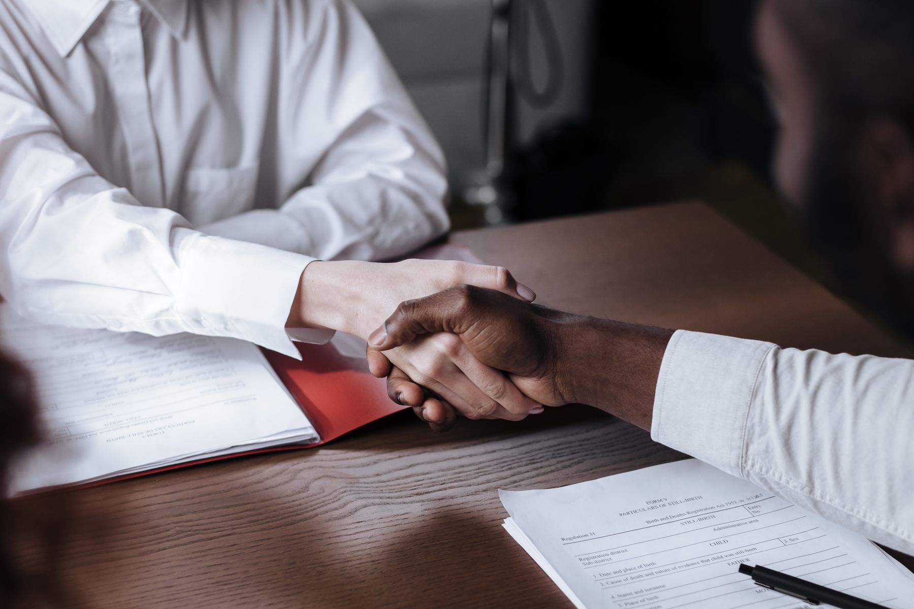 Advisor and investor shaking hands over signed forms