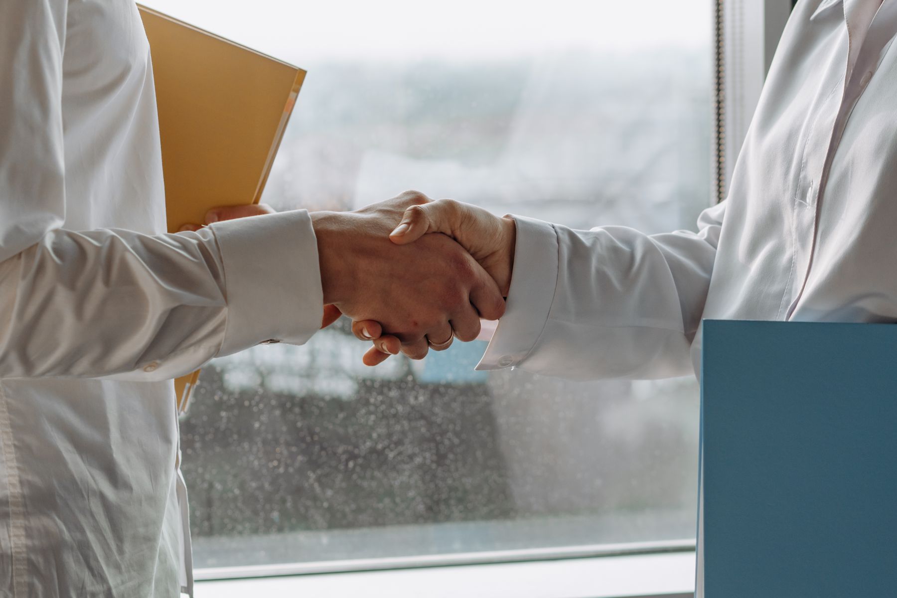 Two people shaking hands across a desk after a planning meeting