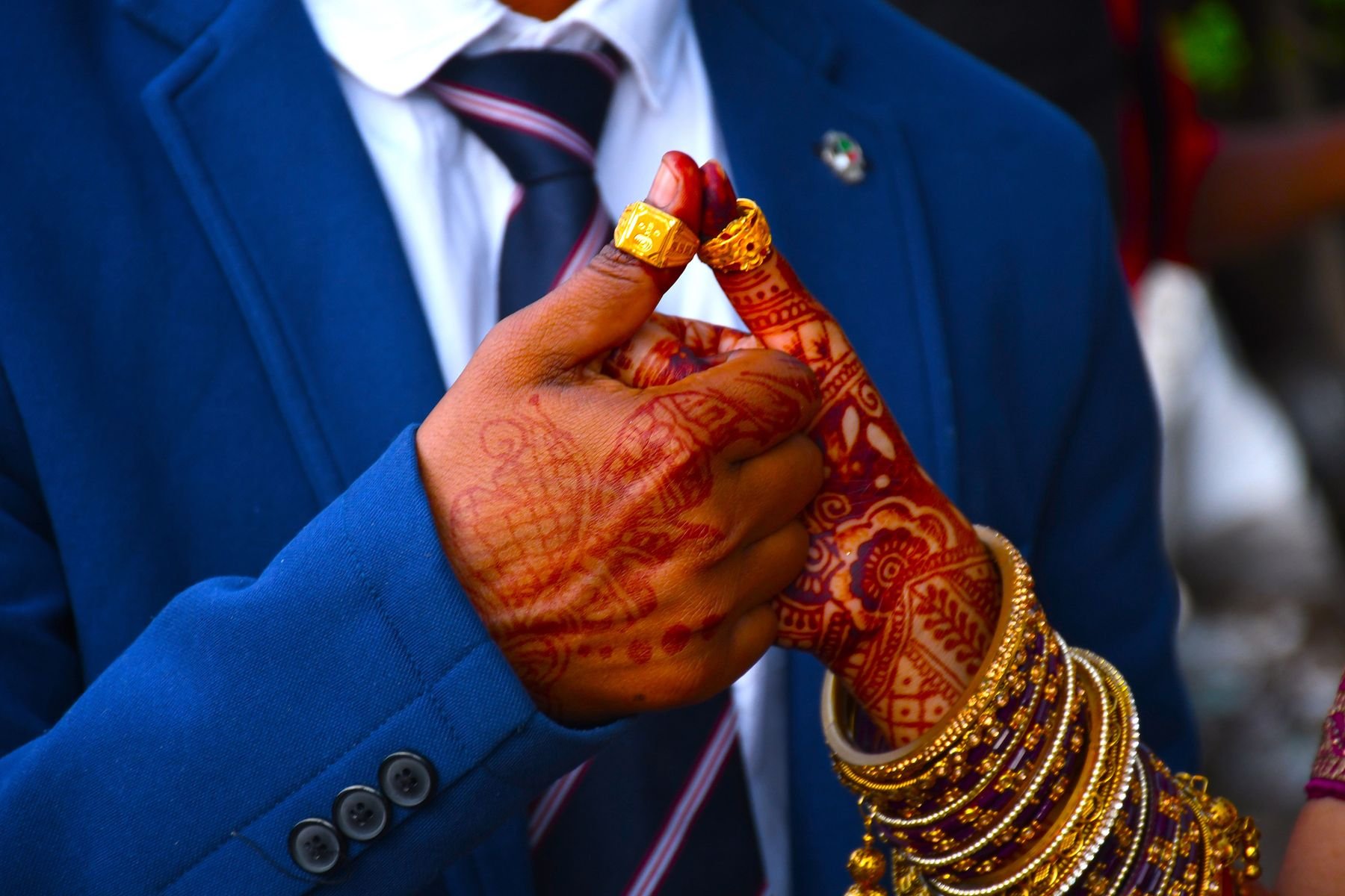 A wedding couple's hands with mehndi and rings
