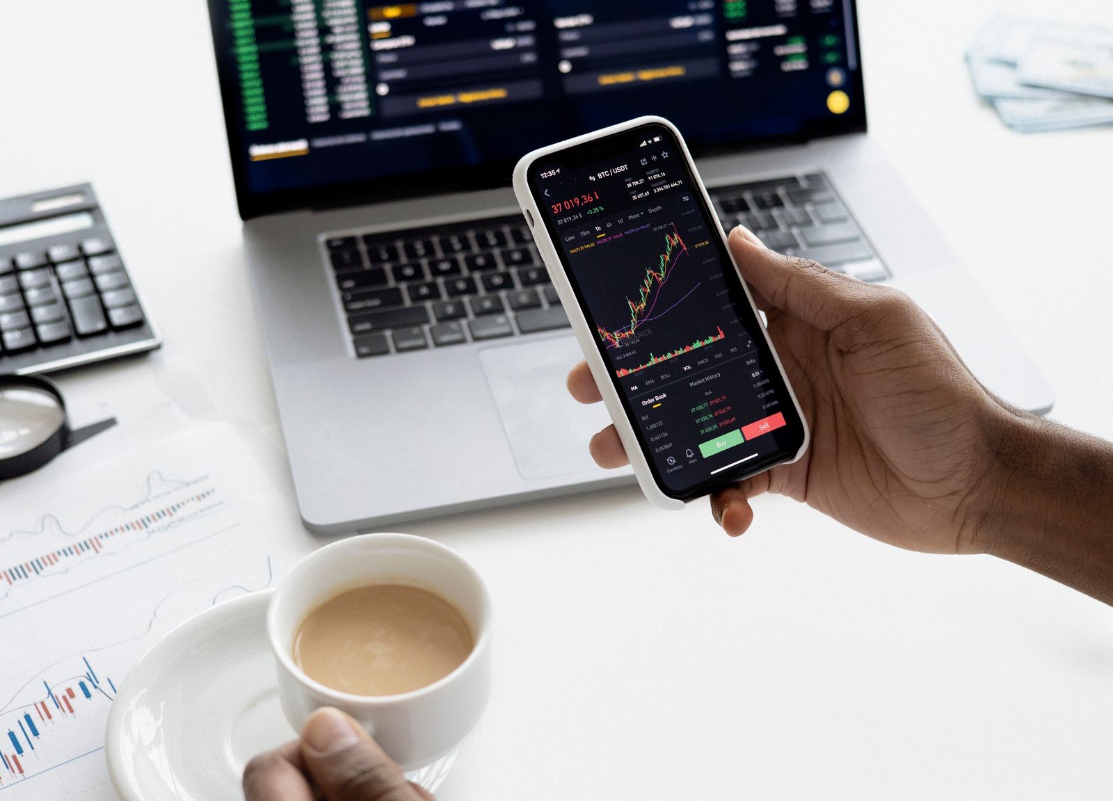 A hand holding a phone showing a market chart