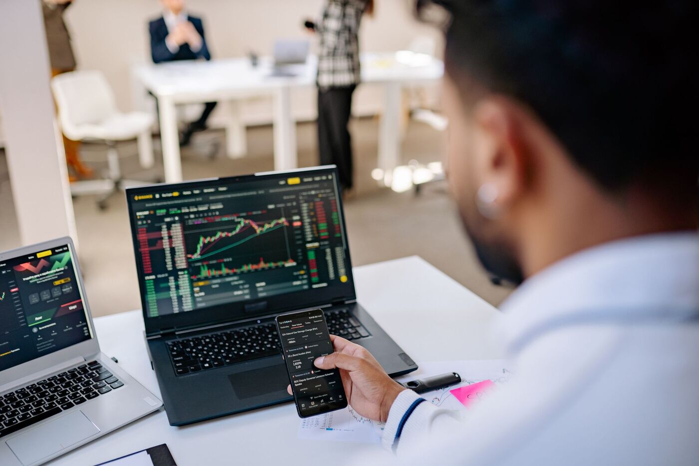A man tracking fund charts on a laptop and phone