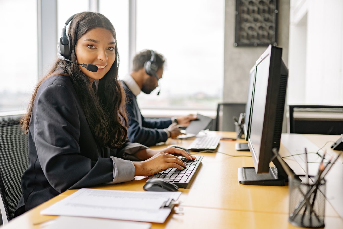 Young woman with a headset smiling at her desk in an office