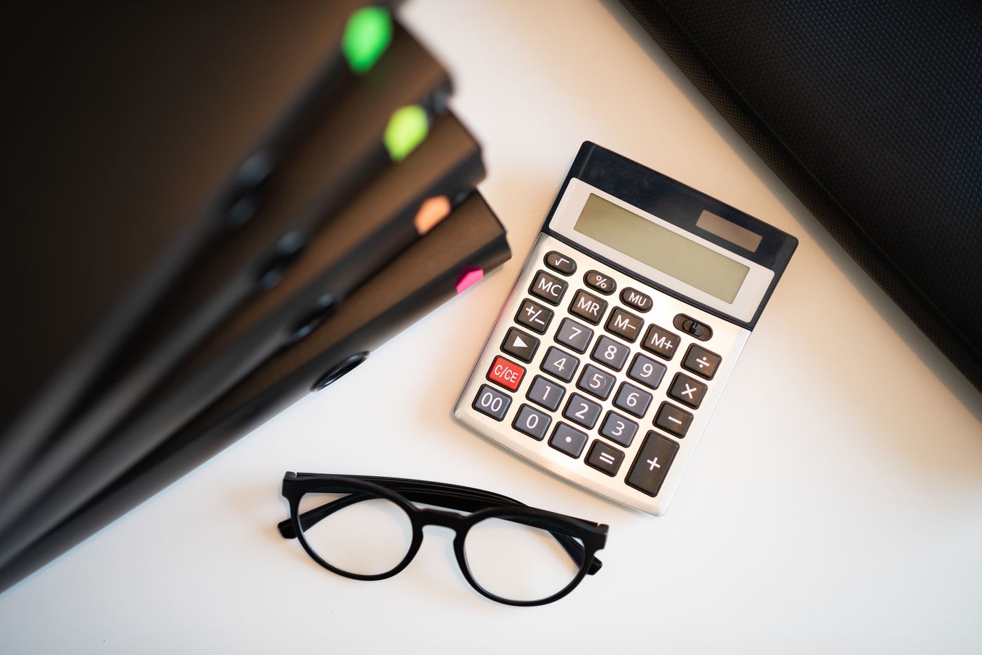 A calculator and reading glasses on a desk