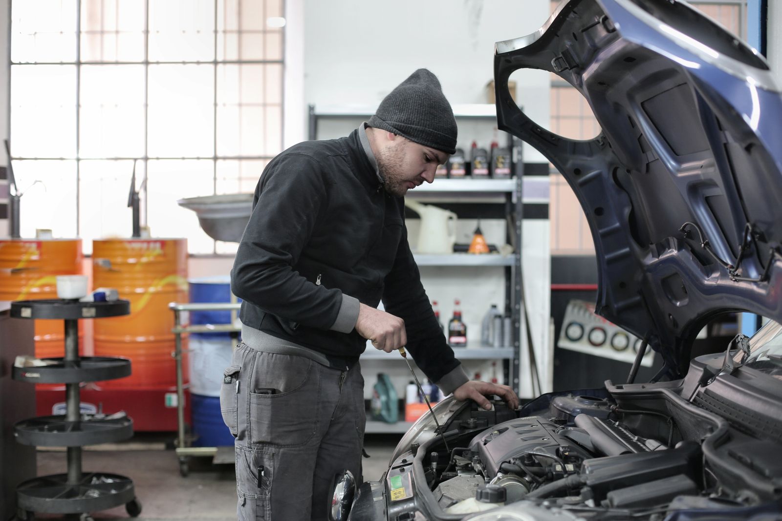 Mechanic working under the bonnet of a car in a workshop