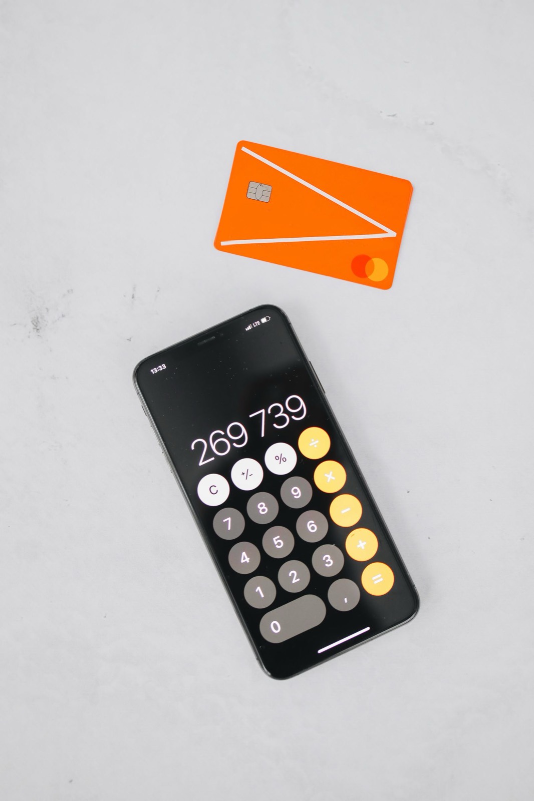 Phone calculator and a debit card on a white table