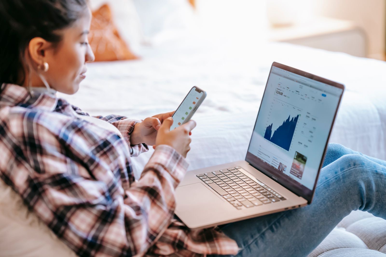 Woman checking an investment chart on her laptop and phone